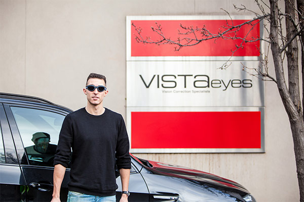 Dylan in front of the Vista Eyes logo with protective goggles
