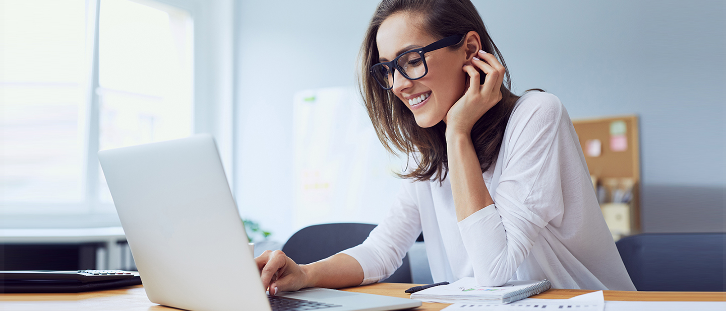 Woman smiling at laptop, representing clear near vision after hyperopia treatment at a Melbourne laser eye clinic